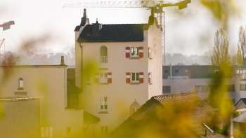 Close-up van de historische toren van het stadhuis van Vaduz met opvallende rode luiken, omringd door bouwkranen op de achtergrond.