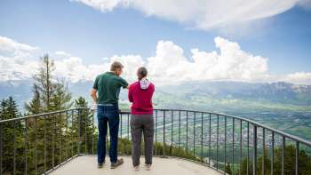 Twee mensen genieten op een heldere dag van het uitzicht vanaf de Gaflei over de Rijnvallei in Liechtenstein.