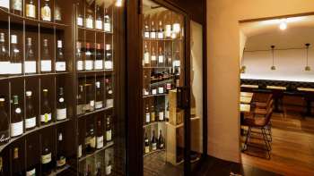 Moderne wijnkast met mooie flessen in de stijlvolle WY Weinbar, uitzicht in het aangrenzende proeflokaal.