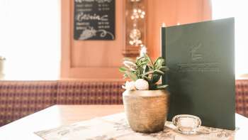 Close-up van een gedekte tafel met menukaarten, bloemen en rustieke decoraties