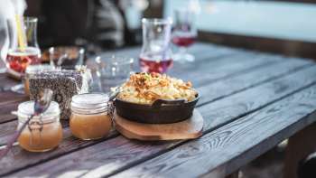 Regionale specialiteit Käsknöpfle met appelmoes op een houten tafel voor een alpine achtergrond