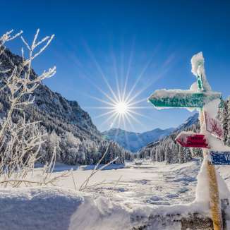 Besneeuwde wegwijzers en een dromerig winterlandschap in de stralende zon in Steg, Liechtenstein.