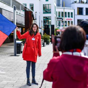 Stadsgids met Liechtensteinse vlag verwelkomt groep toeristen in Vaduz