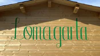 Zicht op het groene Lömagarta-logo, stijlvol aangebracht op de houten gevel van de gezellige biertuin.