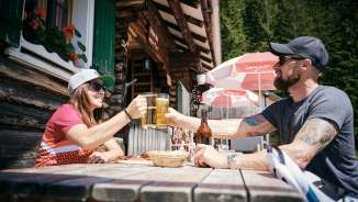 Twee mensen klinken glazen bier voor de Gafadurahütte in de Liechtensteinse Alpen