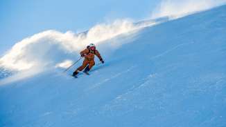 Marco Büchel skiet over een besneeuwde piste in Malbun, de sneeuw dwarrelt achter hem aan.