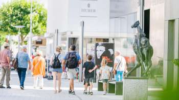 Mensen wandelen door de moderne voetgangerszone van Vaduz langs het Kunstmuseum Liechtenstein