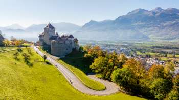 Kasteel Vaduz op een heuvel met uitzicht op de Rijnvallei en de omliggende bergen.