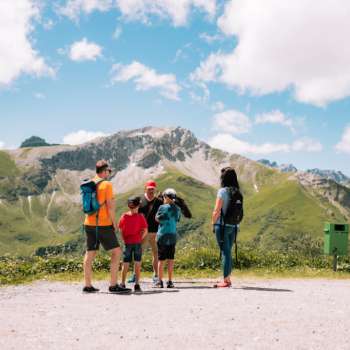 Gezin met kinderen genieten van het uitzicht op de bergen tijdens een valkerijwandeling.