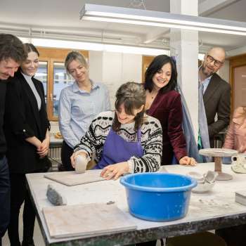 Een groep geïnteresseerde bezoekers kijkt toe hoe een pottenbakker boetseert - een creatieve ervaring in een gezellige sfeer in de keramiekwerkplaats van Schädler in Nendeln.