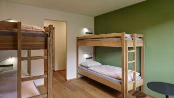 Vierpersoonskamer met stapelbed en houten vloer in jeugdherberg Schaan/Vaduz