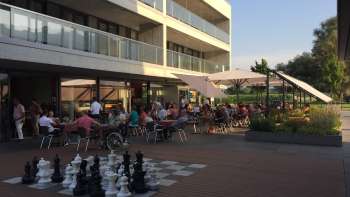 Drukbezocht zonneterras van een modern restaurant met een groot openlucht schaakveld