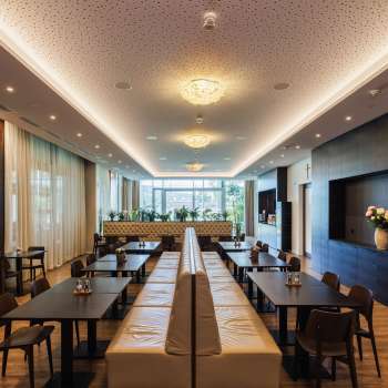 Lichte eetzaal in het Kommod restaurant met stijlvol design en grote ramen.