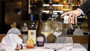 Een ober schenkt witte wijn in bij een elegant gerecht in restaurant Alpspitz.