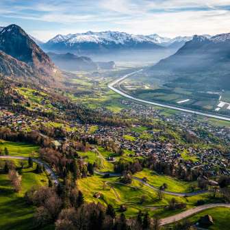 Prachtig uitzicht vanaf de heuvel over de Rijnvallei met velden, dorpen en besneeuwde bergen - een natuurlijke idylle in Liechtenstein