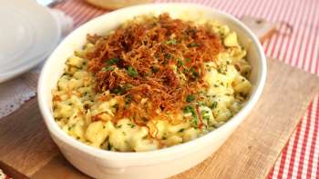 Traditionele Käsknöpfle met gebakken uien - geserveerd in een bord op een houten plank