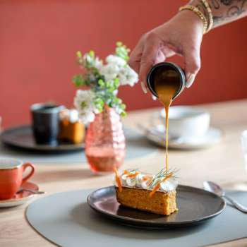 Dessert overgoten met karamelsaus, koffiekopjes en stijlvolle tafeldecoraties op de achtergrond