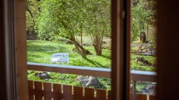 Uitzicht vanaf het balkon van het pension op camping Mittagsspitze in het groen met bomen en ligweide.