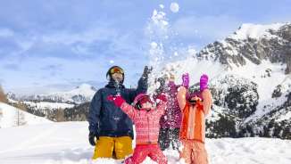 Gezin geniet samen van de sneeuw in Malbun - kinderen gooien vrolijk sneeuwballen tegen een winters bergdecor.
