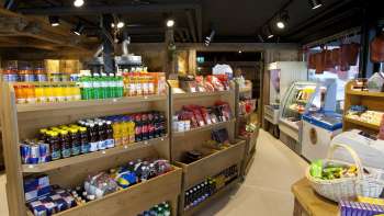 Binnenzicht van de Malbuner Läderli met houten schappen vol regionale producten, drankjes en snacks.