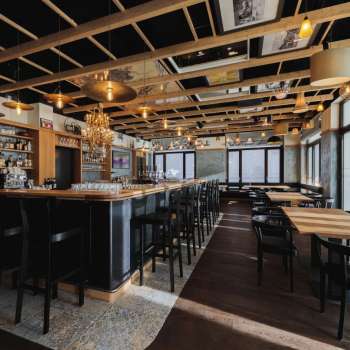 Licht interieur van de St. Martins Pub met bar, houten meubels en grote ramen.