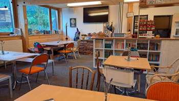 Zicht op de eetkamer met houten wand en wanddecoratie - verschillende tafels met zitplaatsen en zicht op de decoratieve wand met gitaren en groene afbeeldingen.