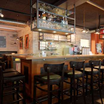 Stijlvolle interieurfoto van de bar in het New Castle Vaduz met een goed gevuld flessenrek en gezellige zithoek.