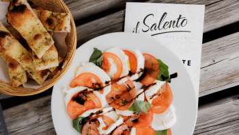 Verse pizza met tomatensaus en rucola, geserveerd op een rustieke houten tafel