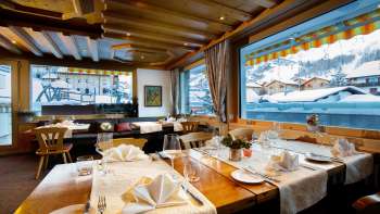 Lichte, uitnodigende eetkamer met grote ramen en uitzicht op besneeuwde bergtoppen