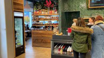 Klanten bij de kassa, omringd door uitnodigende houten decoraties en verse producten