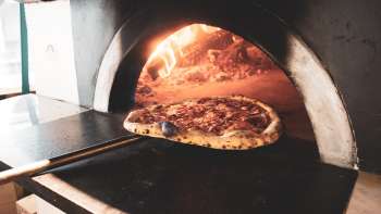 Pizza in een houtoven met een goudbruine korst en knapperige korst Pizza in een houtoven met een goudbruine korst en knapperige korst