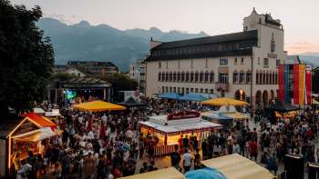 Het stadshuis Vaduz in de schemering met feeërieke lichtjes, spelende kinderen op een pingpongtafel en een zomerse sfeer op de feestdagen
