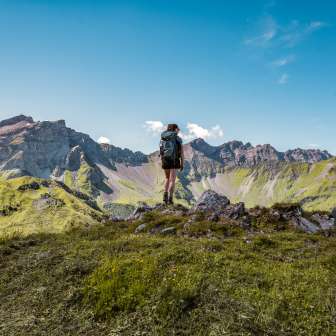 Wandelaar op een bergtop in Liechtenstein met uitzicht op een indrukwekkende bergketen - zomer, vrijheid en pure natuur