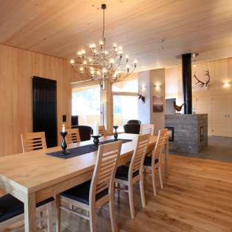 Lichtgekleurd houten interieur met eettafel en open haard in Haus Ochsenkopf in Malbun, Liechtenstein
