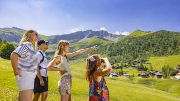 Familie kijkt in de verte in het alpenlandschap met uitzicht op de bergen in de zomer