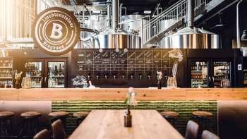 Gezellige tapkamer in het Liechtensteiner Brauhaus met houten tafels, tapinstallatie en uitzicht op de brouwketels